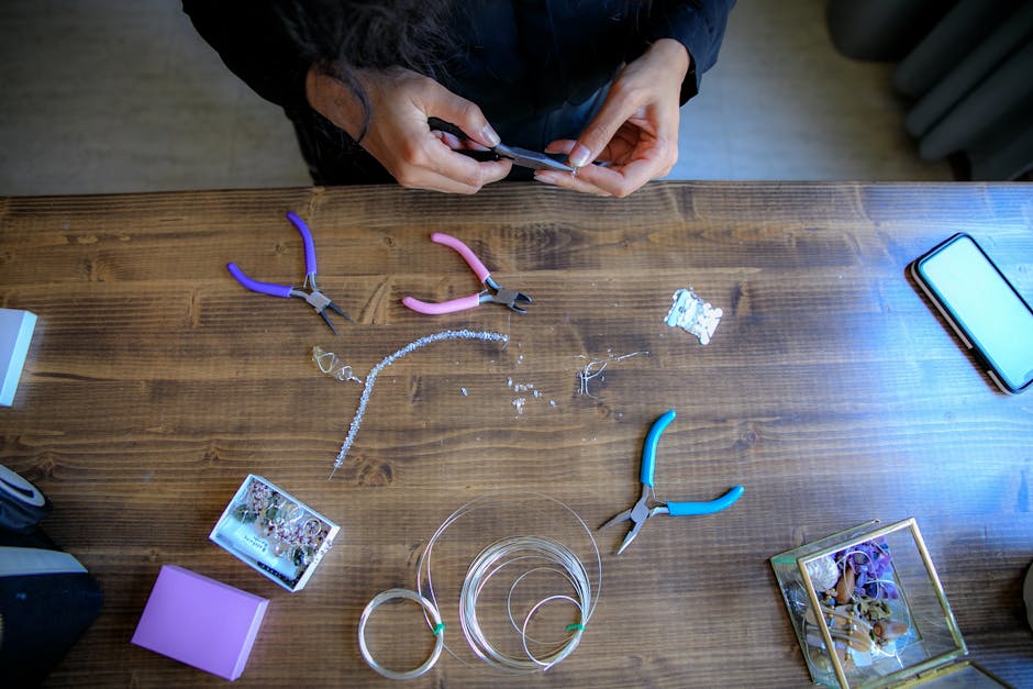 An artist working on handmade jewelry in a well-organized home studio, surrounded by craft supplies and finished products