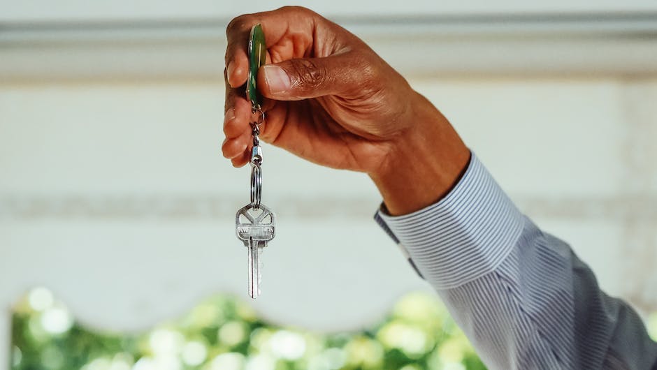 Image description: A person holding a key in front of a new house.